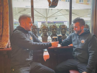 two men sitting with a pint of guinness
